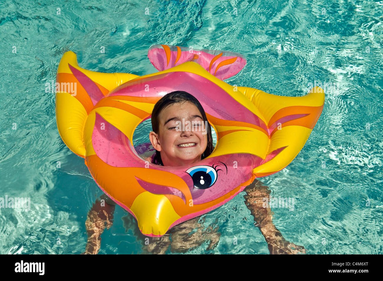 A cute girl acting silly with a colorful inner tube in the water Stock