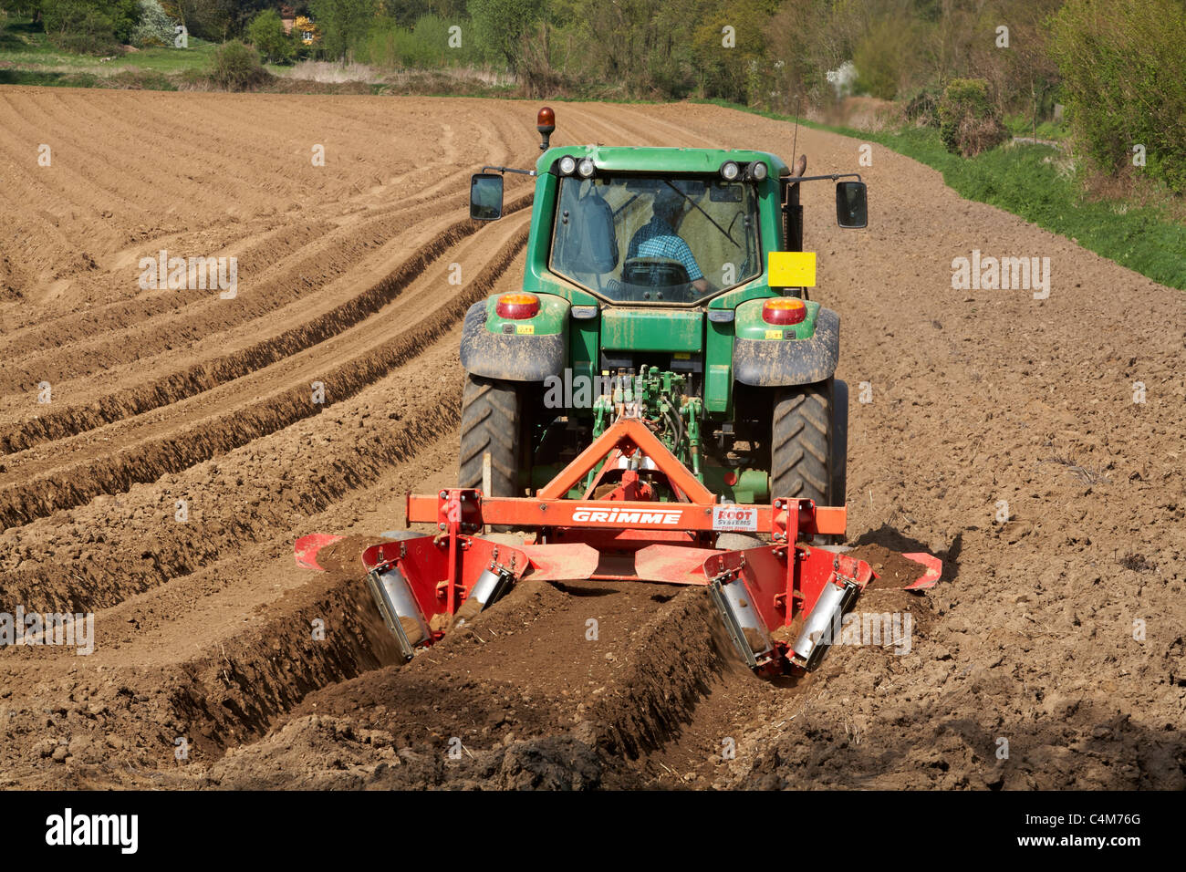 Working Agricultural Tractor with machinery for making furrows in field