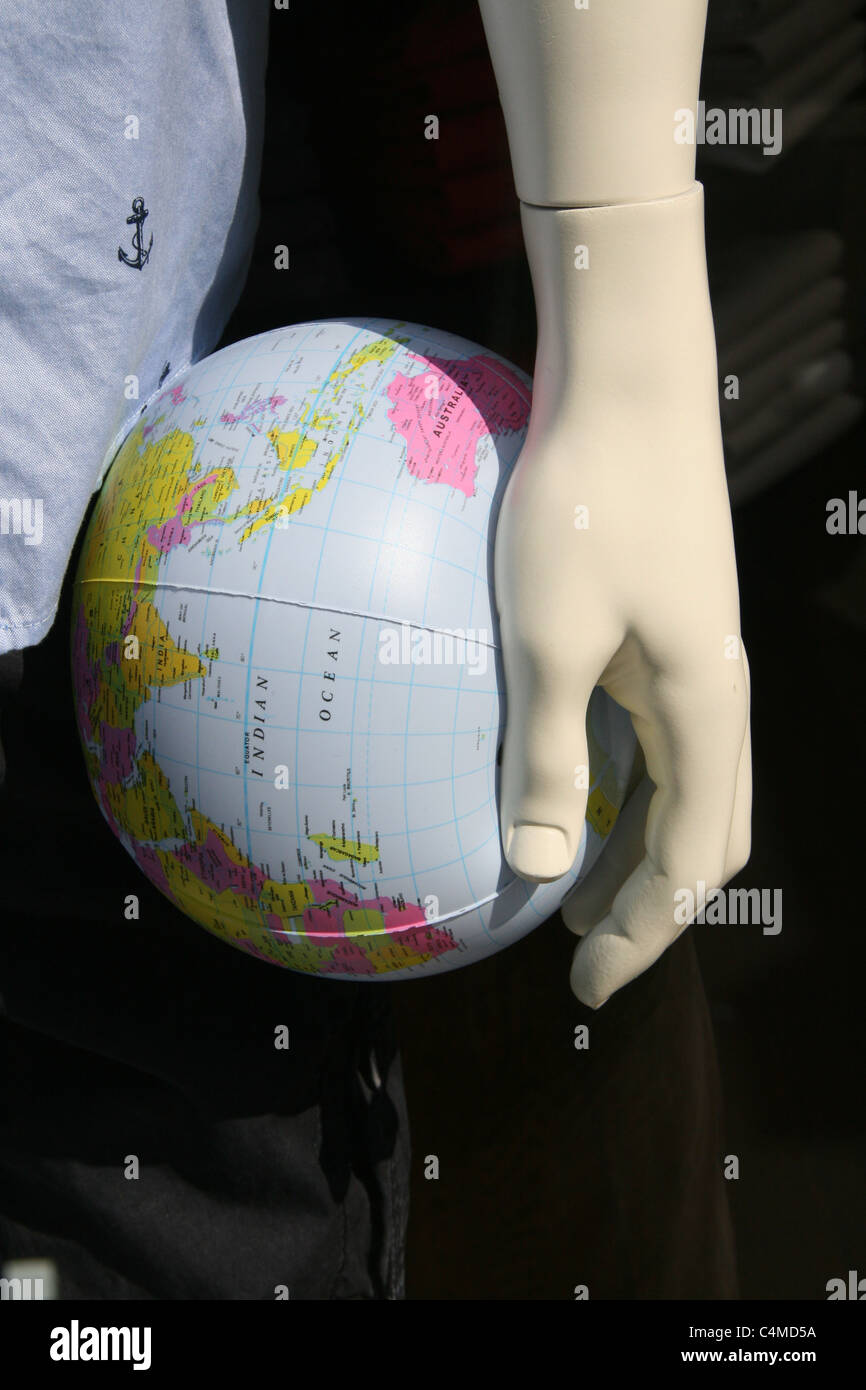 inflatable world map globe in mannequin doll hand in shop window Stock Photo