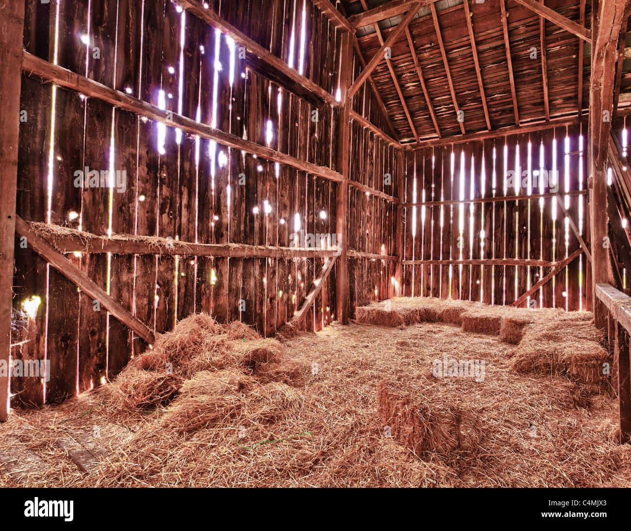 Old Barn with the sun streaming from outside and straw and hay on the floor of the hayloft, USA Stock Photo