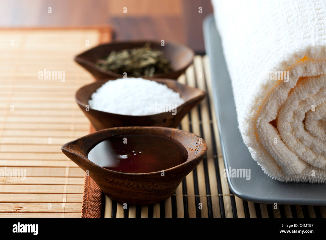 natural bath supplements in small wooden bowls, arranged with rolled towel and bamboo mats Stock Photo