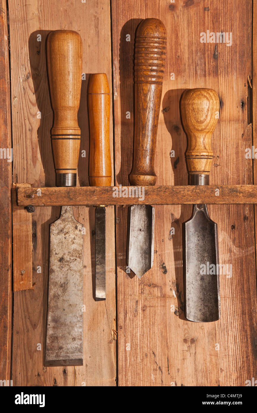 Verschiedene Werkzeug zur Holzbearbeitung hängen an einer Holzwand | Various tools for woodworking hanging on a wooden wall Stock Photo