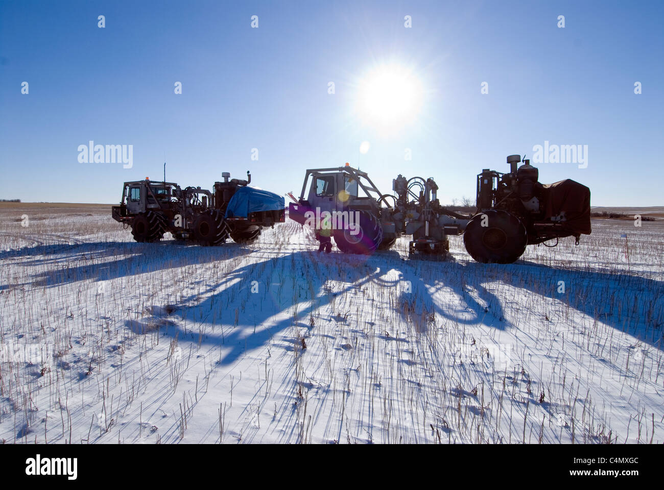 Workers around seismic vibrator trucks that are used for oil & natural