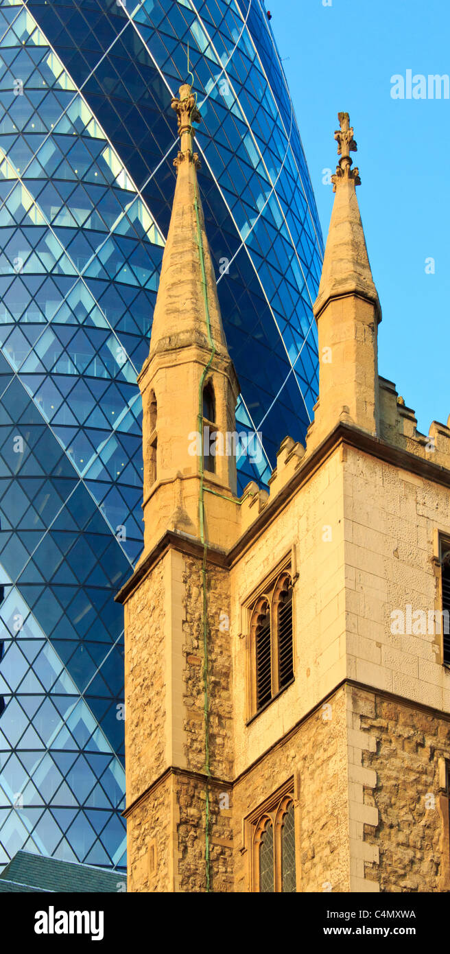 30 St Mary Axe, better known as the Gherkin, rises behind St Andrew Undershaft church in the City of London Stock Photo