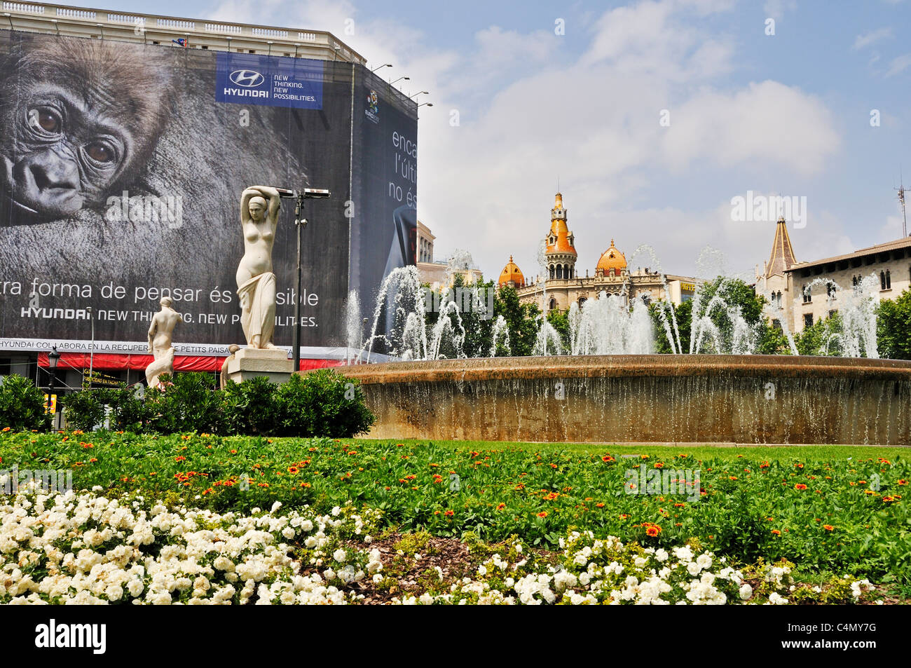 One of the many fountains in Plaça de Catalunya bordered by an advertising hoarding and modern neo-Gothic buildings, Barcelona Stock Photo