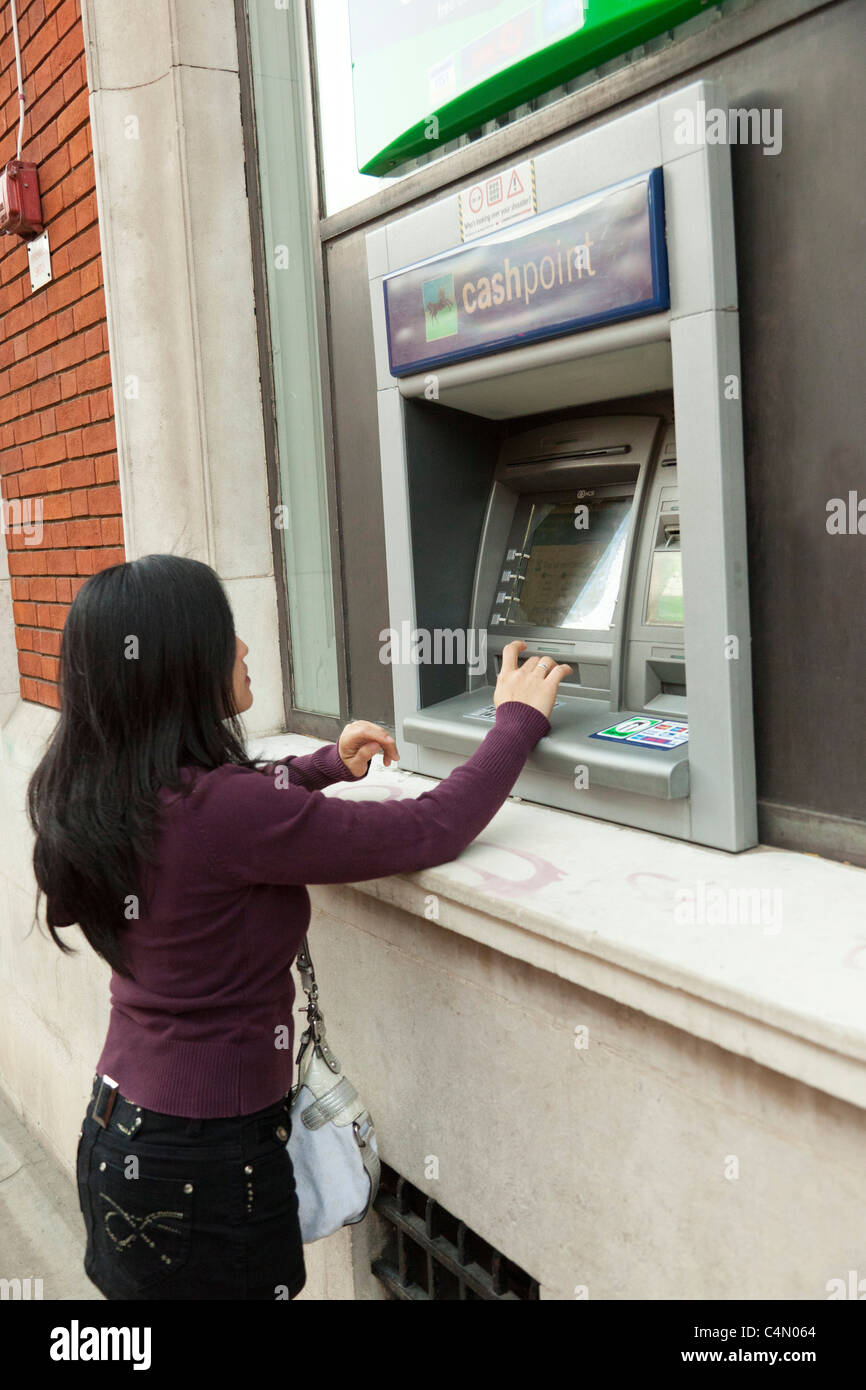 young woman using cash machine / ATM Stock Photo