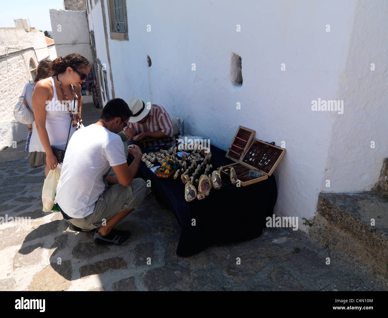 Chora Patmos Greece People Looking At Stall Selling Religious Artefacts And Jewellery In Narrow Street Stock Photo