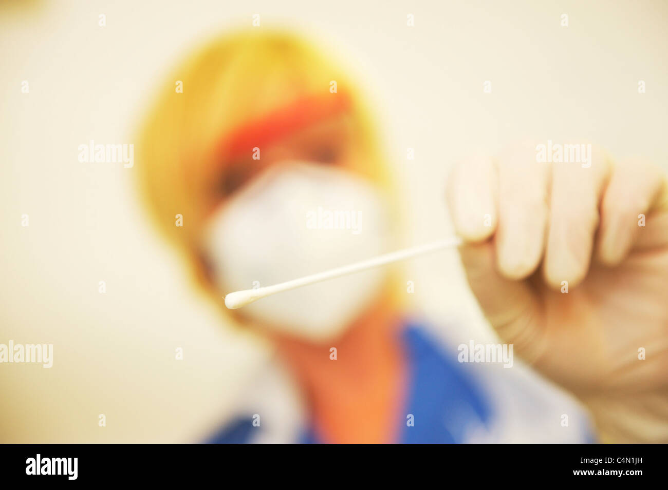 A UK Nurse wearing a face mask holds a swab towards to the camera, after taking a sample from the patient Stock Photo