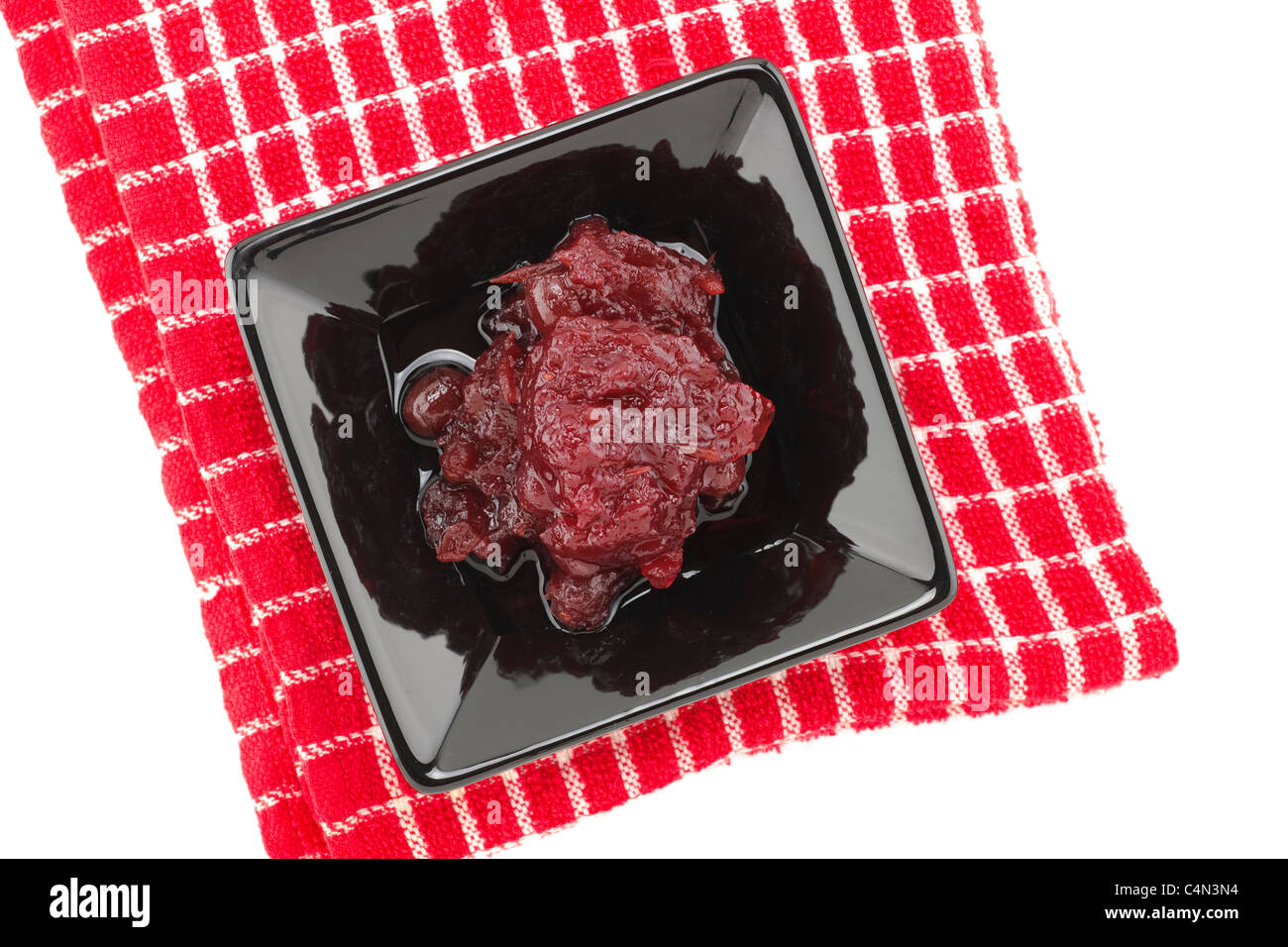 Cranberry sauce in a black serving dish placed on a red and white teatowel Stock Photo