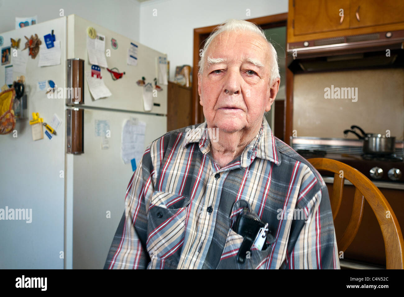 A retired elderly Senior Man in his home sitting on a chair. Stock Photo