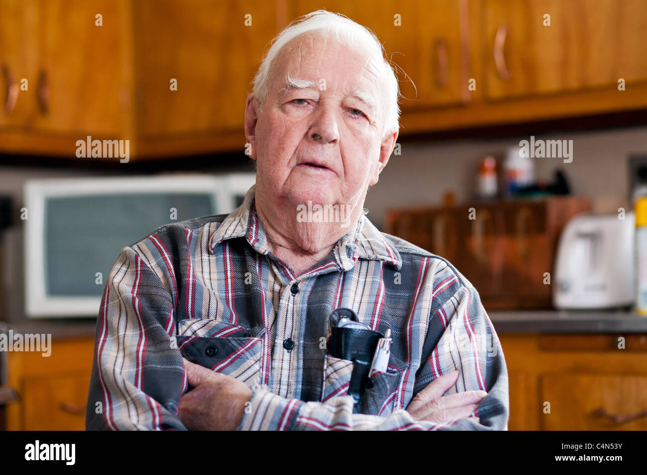 A retired elderly Senior Man in his home sitting on a chair. Stock Photo