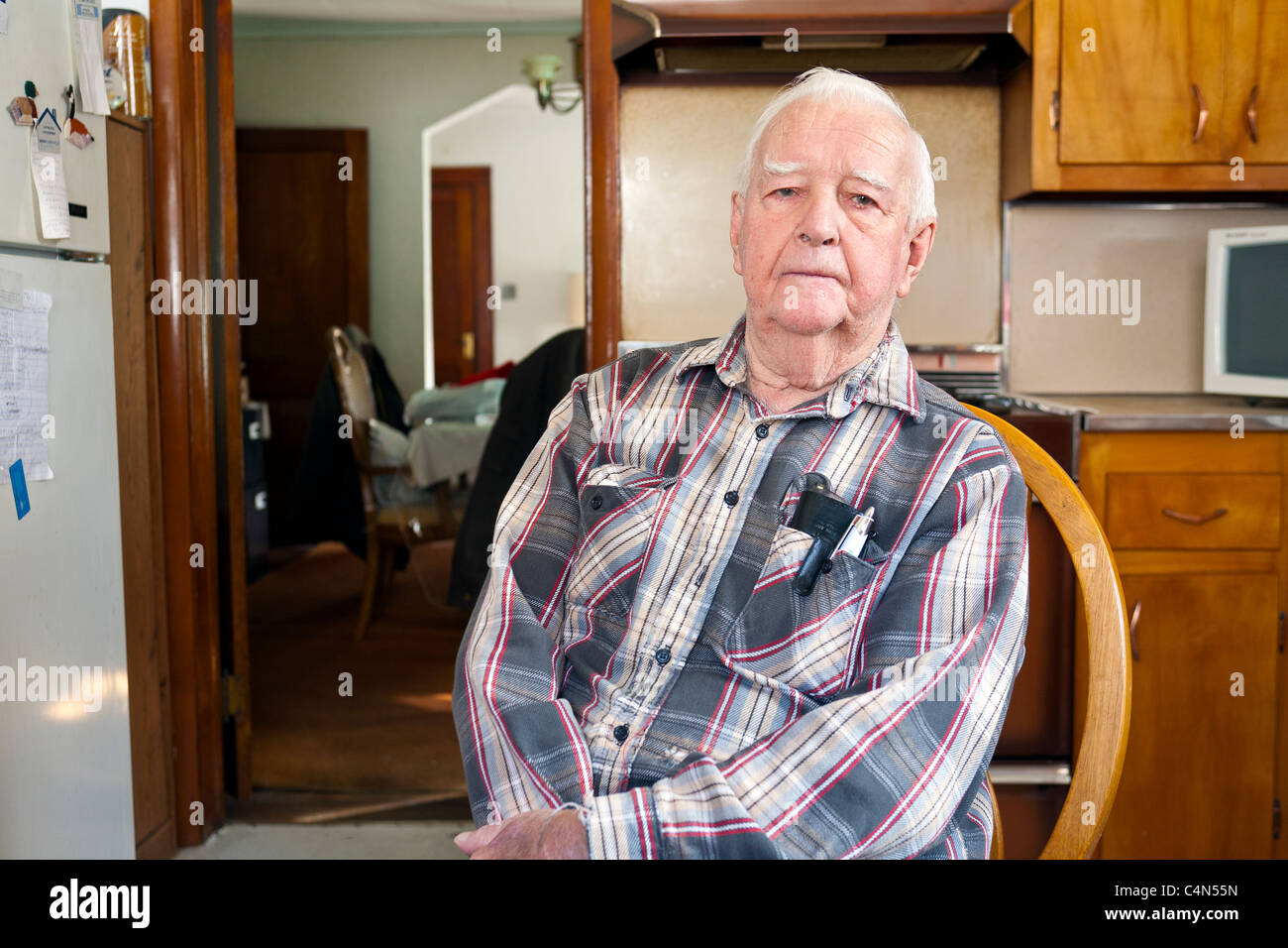 A retired elderly Senior Man in his home sitting on a chair. Stock Photo