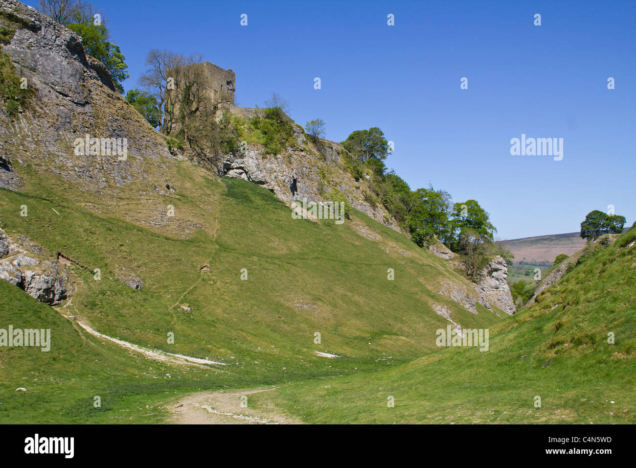 Looking up at Peveril Castle from the path through CaveDale, Castleton Stock Photo