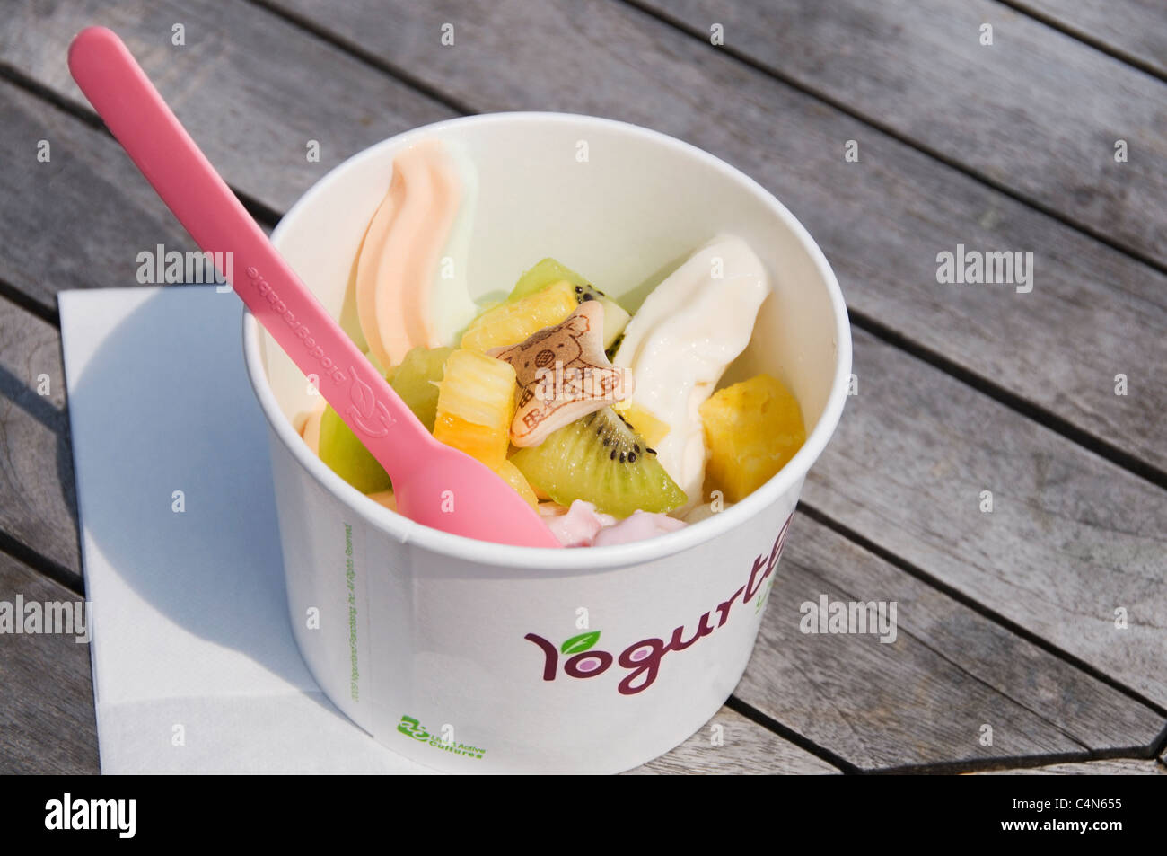 A cup of flavorful self-serve soft frozen yogurt is topped with an assortment of fresh fruit and a Koala Yummie in Okinawa Japan Stock Photo