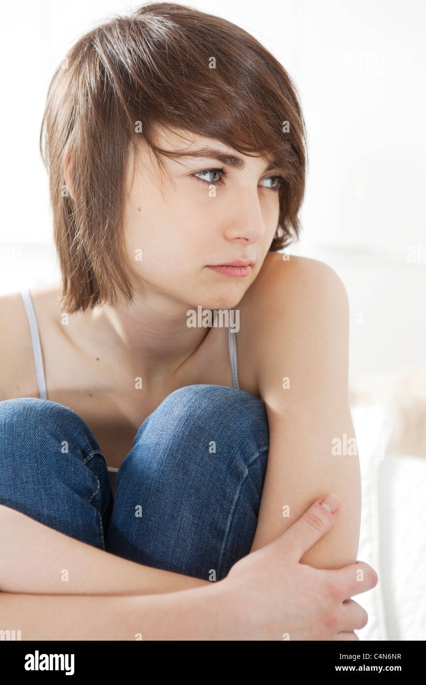sad girl sitting on the bed hugging her knees Stock Photo - Alamy
