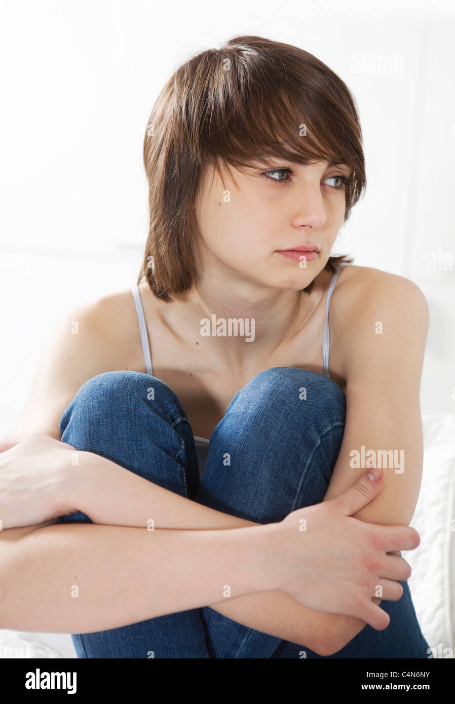 sad girl sitting on the bed hugging her knees Stock Photo - Alamy