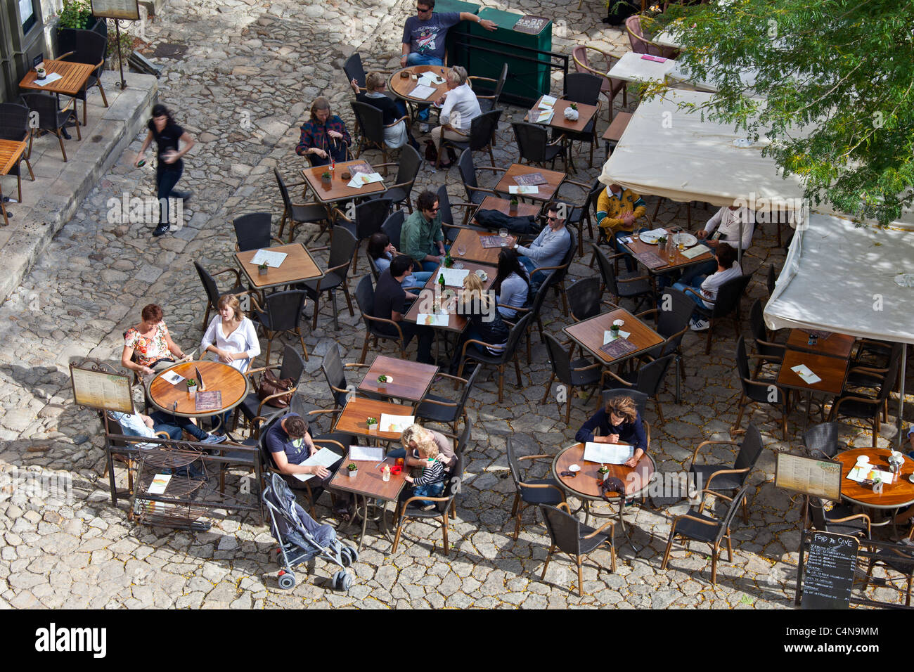 Diners at pavement cafe and cobbled pavement in St Emilion, Bordeaux region of France Stock Photo