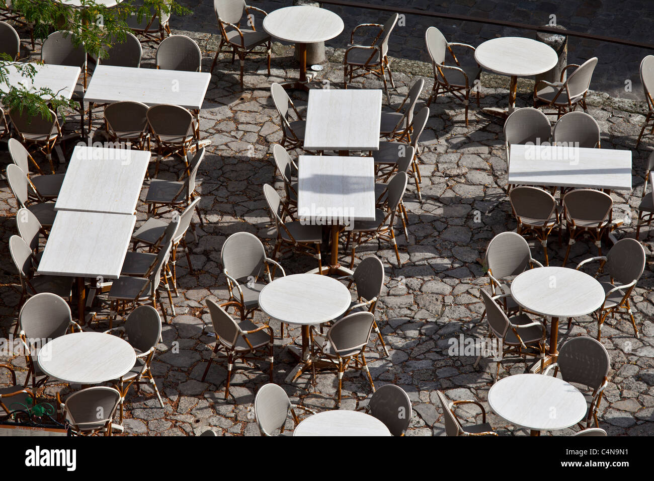 Empty tables at pavement cafe and cobbled pavement in St Emilion, Bordeaux region of France Stock Photo