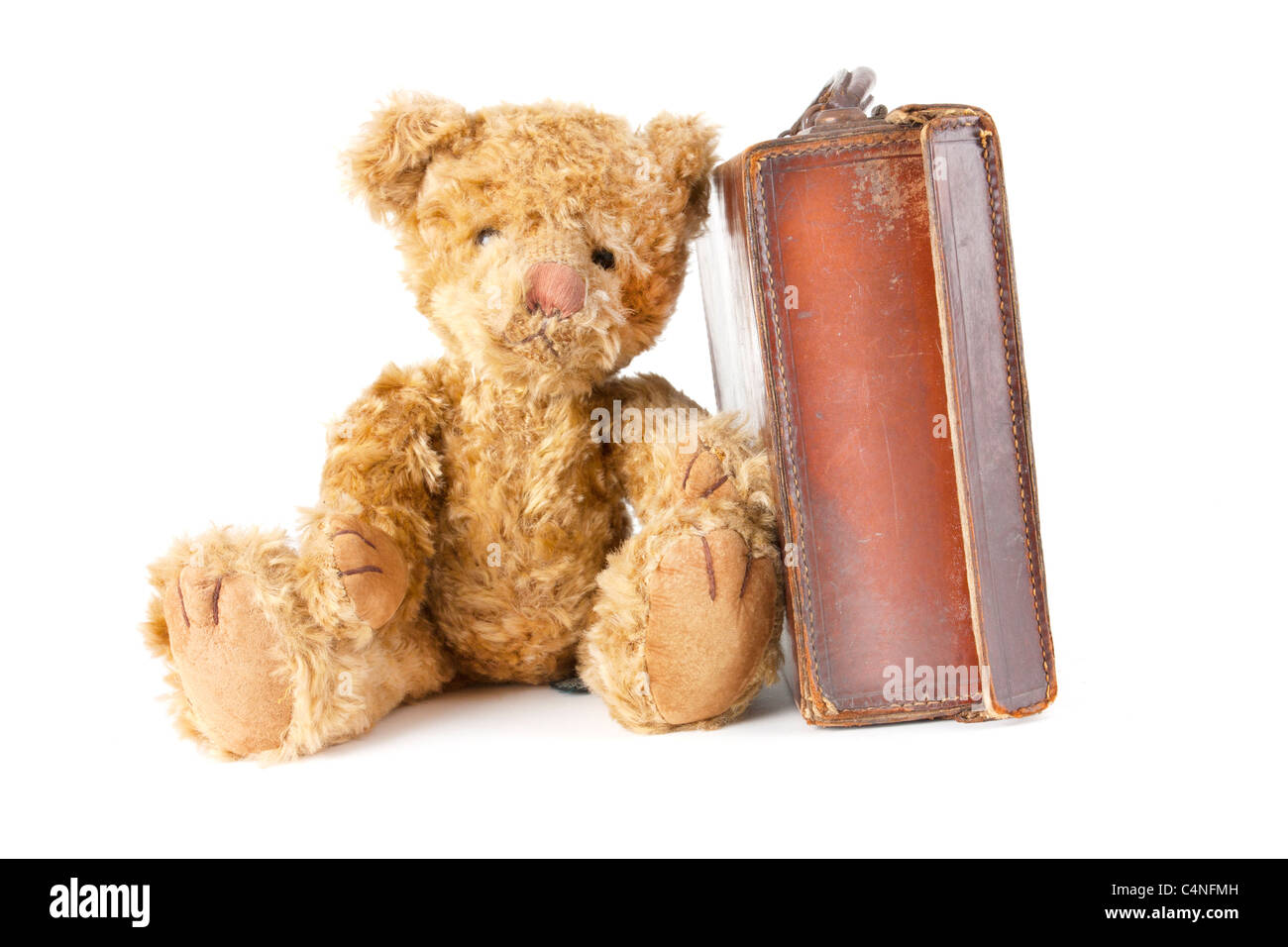 childs teddy bear sitting next to an old vintage suitcase Stock Photo