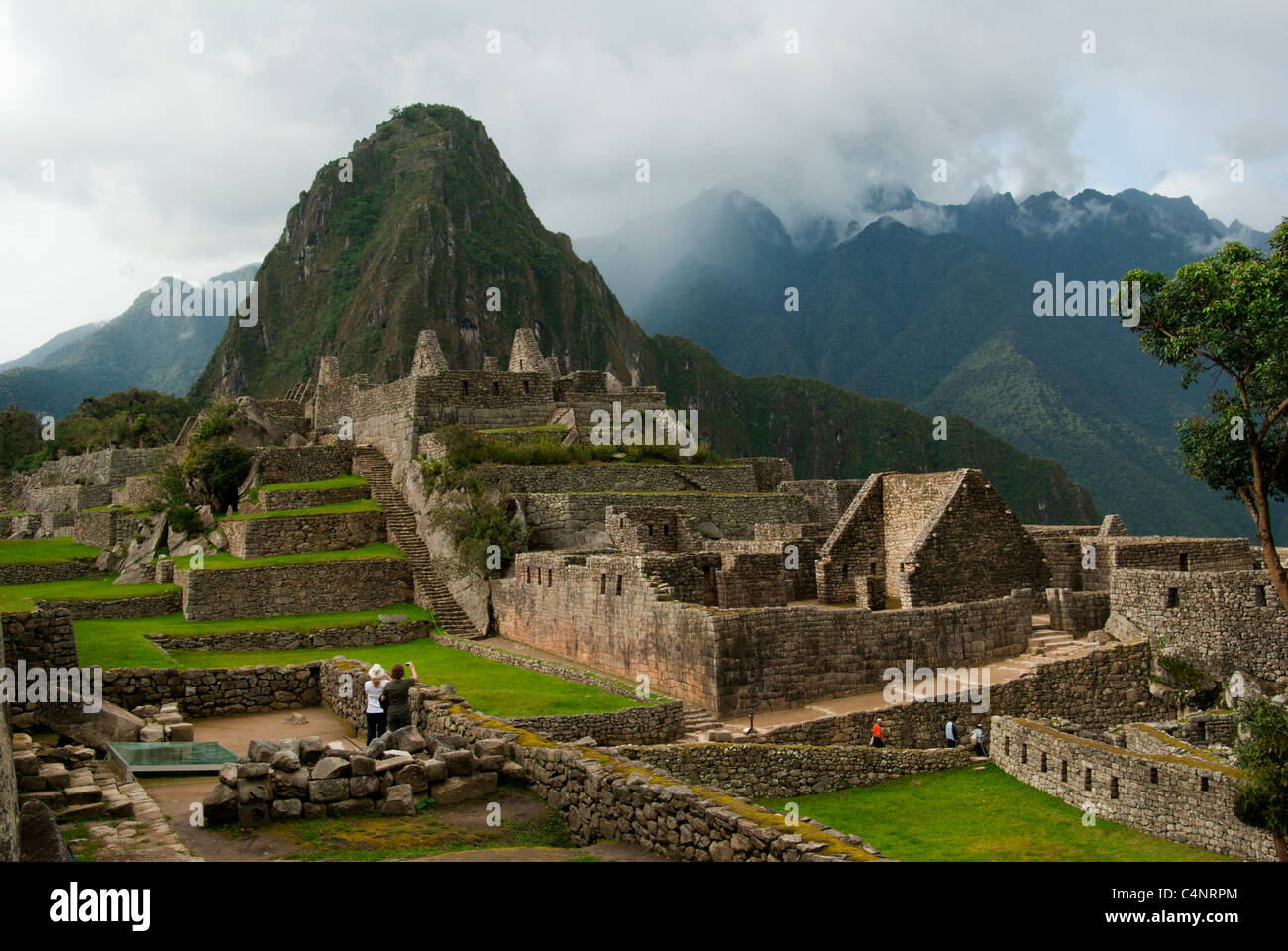 Two women photographing ruins and Wayna Picchu, Machu Picchu, Peru Stock Photo