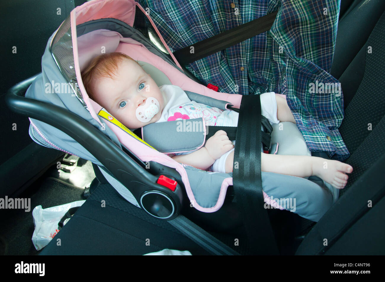 beautiful, small girl with pacifier, sitting in a car seat Stock Photo