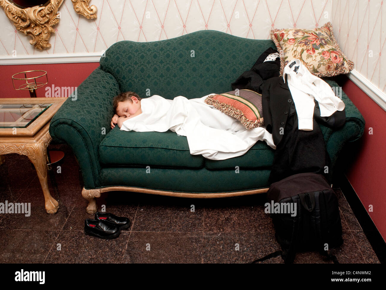 A fiveyearold boy sleeping on a couch in a hotel lobby Stock Photo