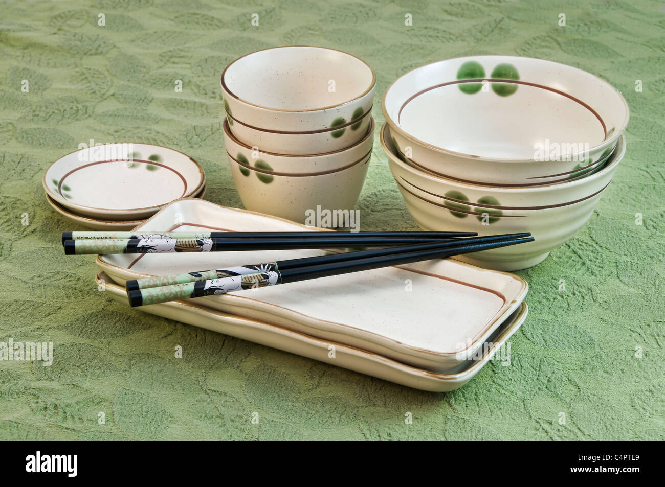 Stacked contemporary Japanese dishes including rectangular plates, rice bowls, tea cups and chopsticks. Stock Photo