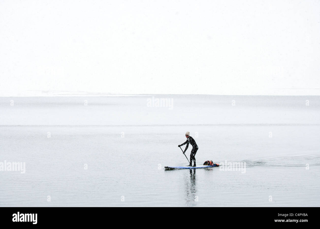 Man Paddle Boarding in a Snow Storm Stock Photo