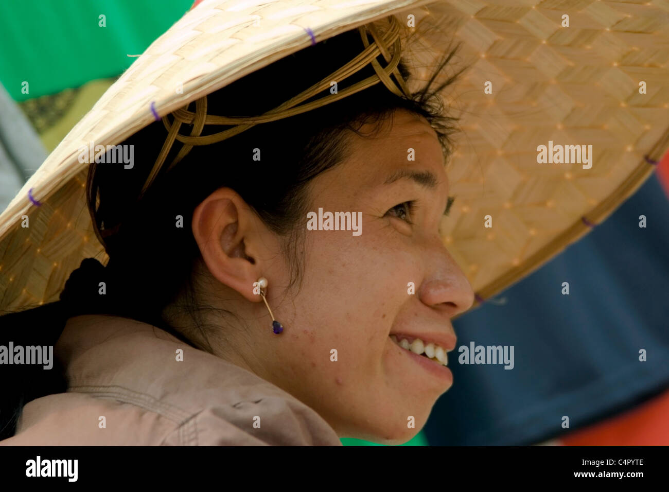 An Asian woman wearing a straw hat is selling goods at a street market in Luang Prabang, Laos. Stock Photo