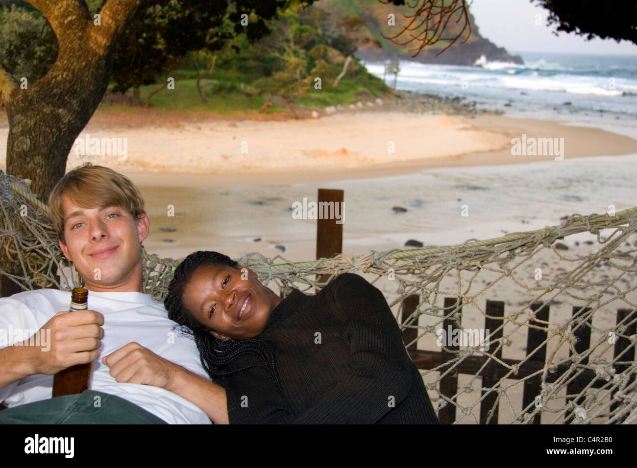 A couple relaxes in a hammock by the beach, Transkei, South Africa Stock Photo
