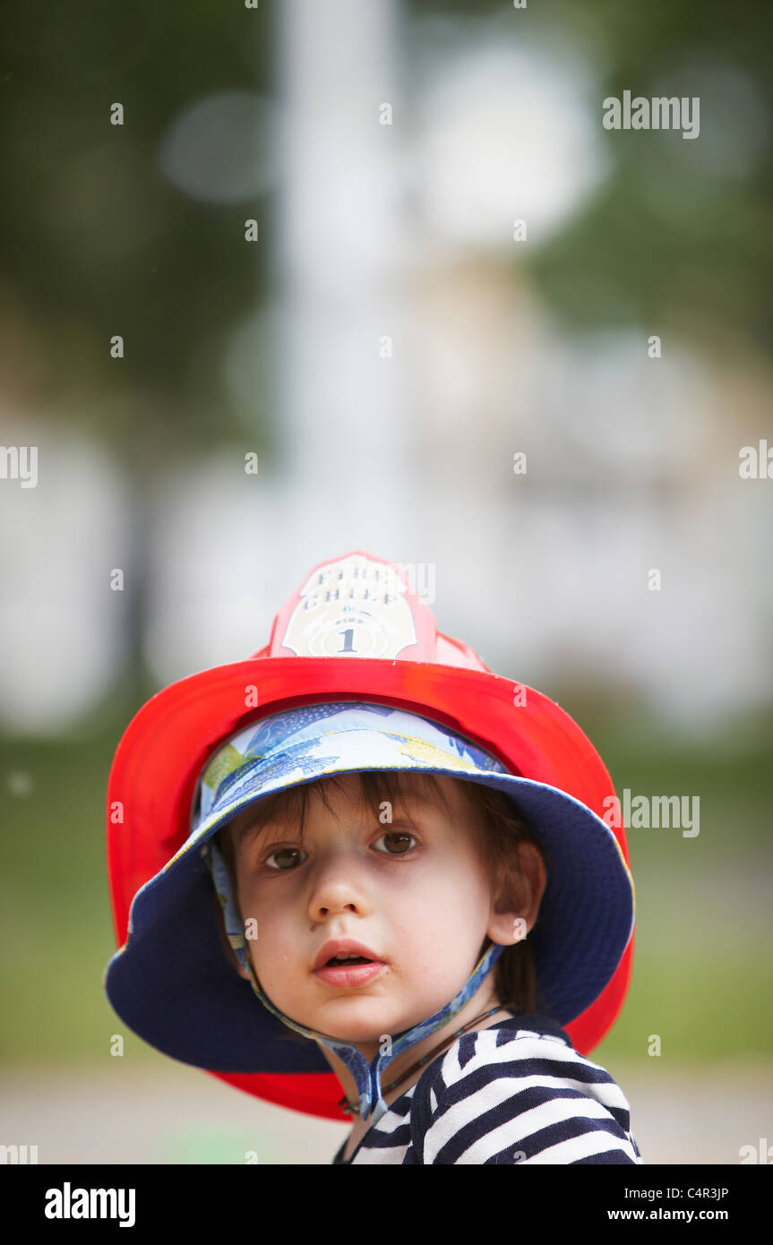 Portrait of little boy in fireman hat, Montreal, Quebec, Canada Stock Photo