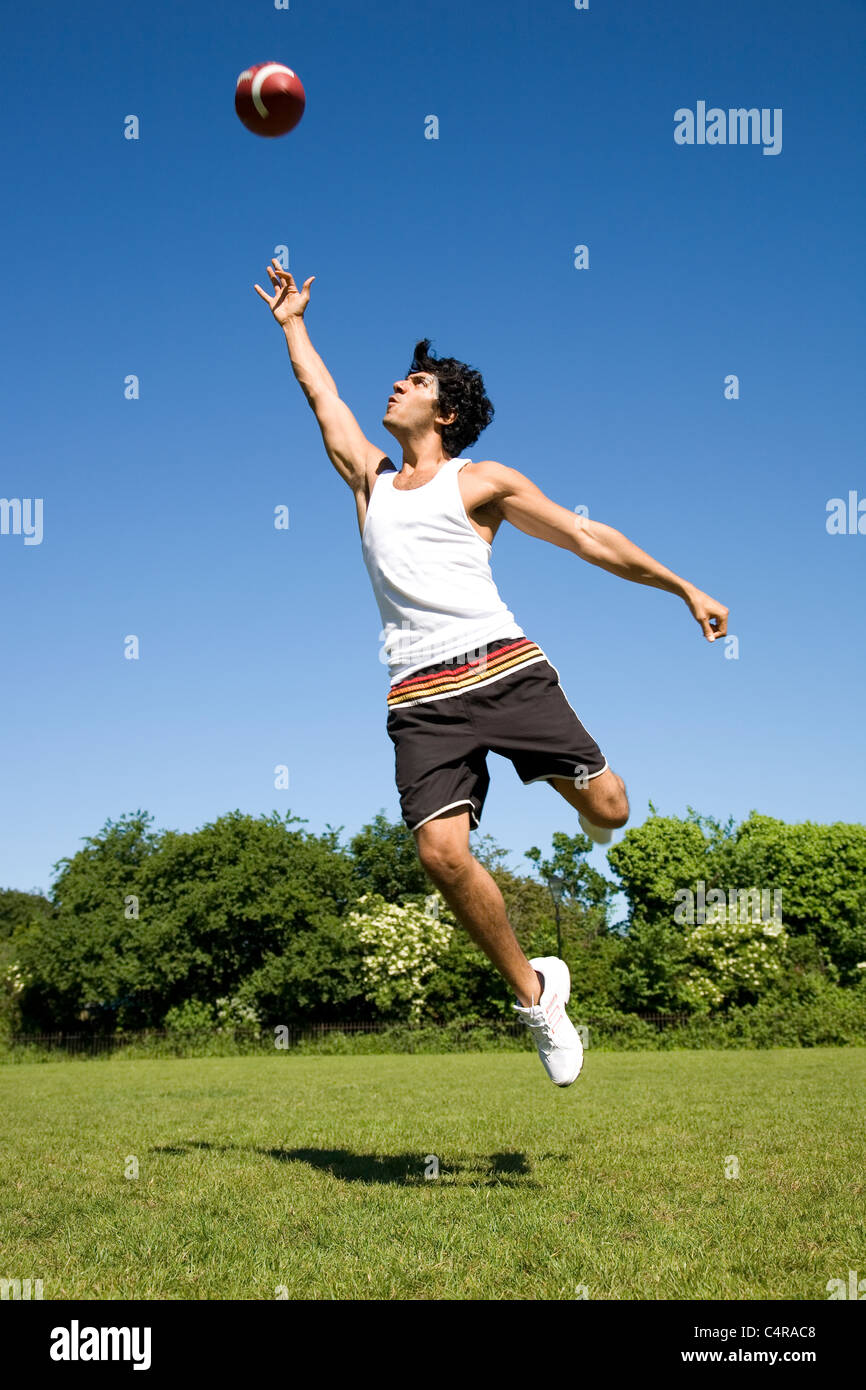 Man jumping playing with oval ball in park Stock Photo Alamy
