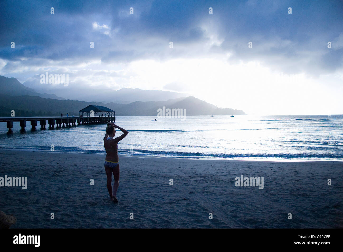 Woman enjoys sunset over Hanalei Bay, Kauai, Hawaii, USA Stock Photo