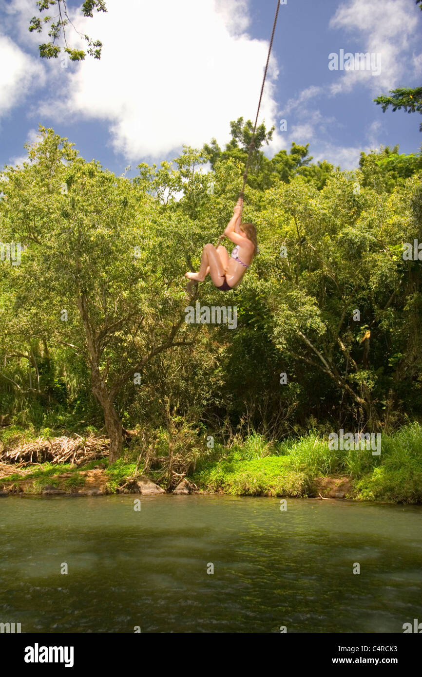 Swinging over secret local swimming hole, Kipu Falls, Kauai, Hawaii