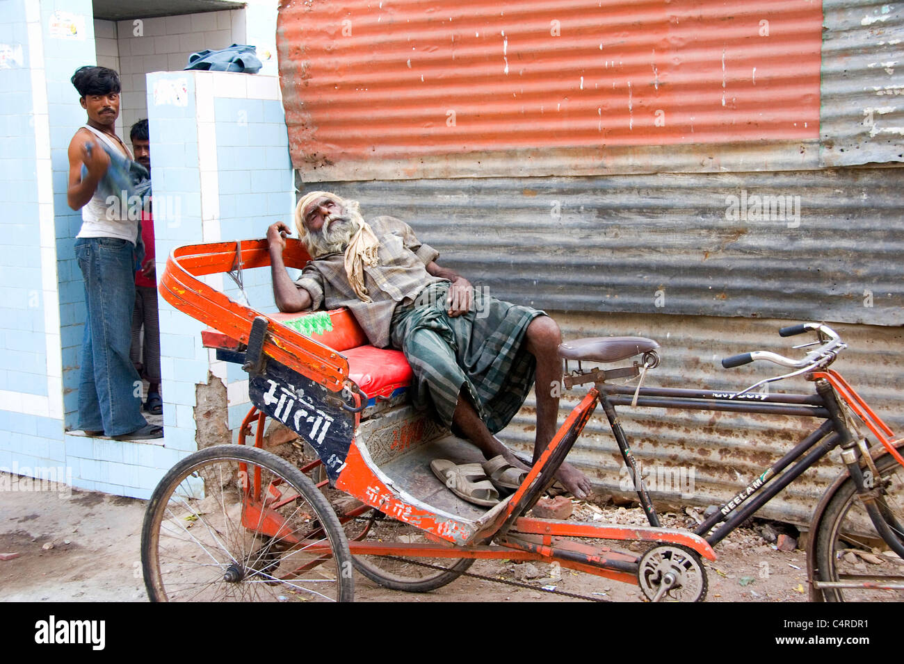 An Indian rickshaw driver collapses in exhaustion, Delhi, India Stock Photo