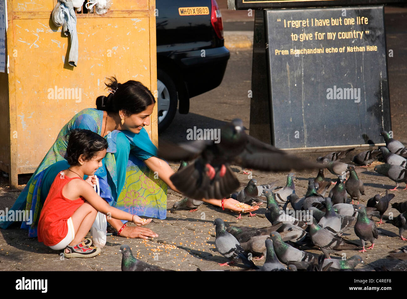 Indian mother and daughter feeding birds in the shadows of the Gateway