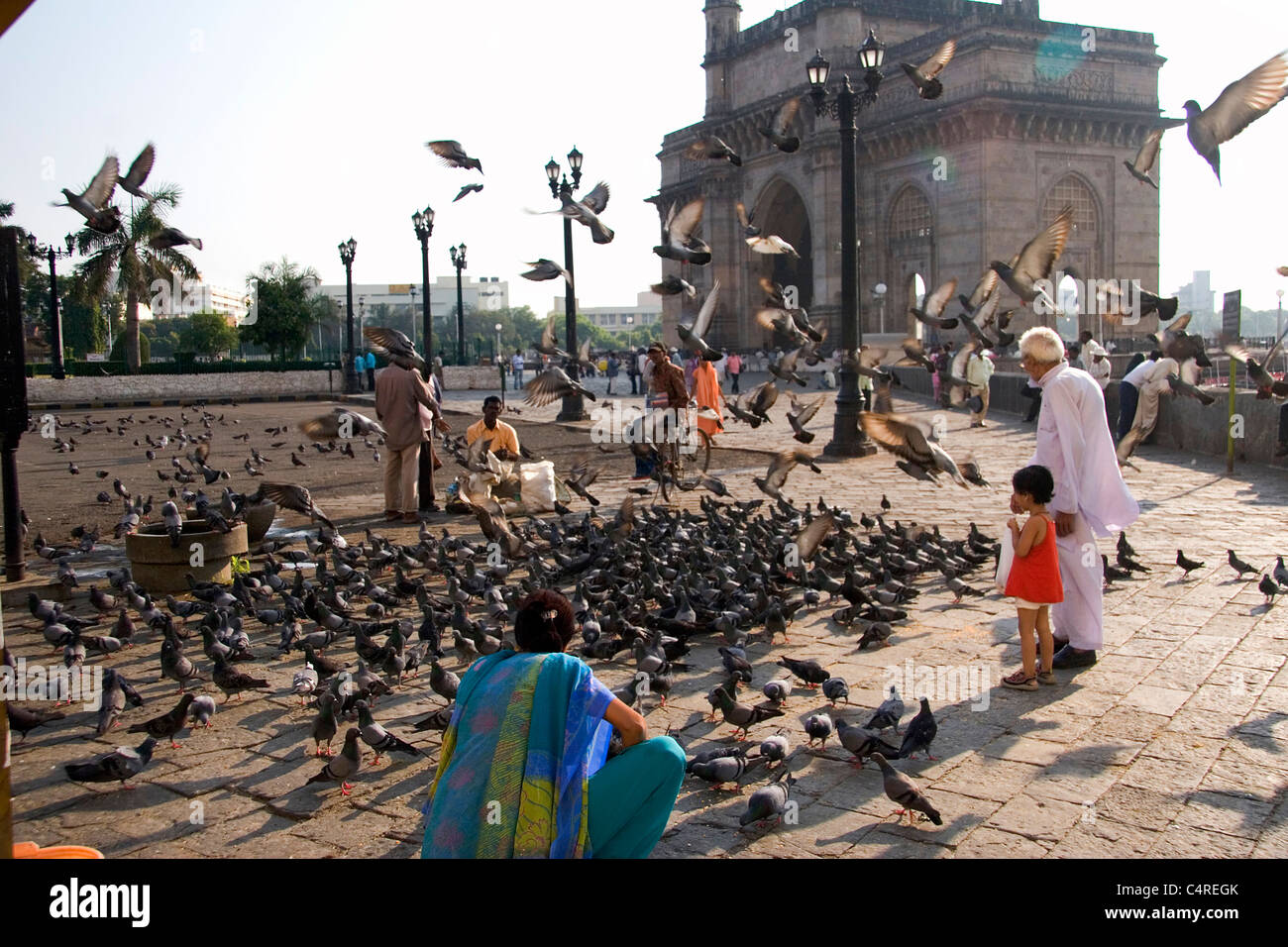 Feeding birds in the shadows of the Gateway of India, Mumbai, India Stock Photo