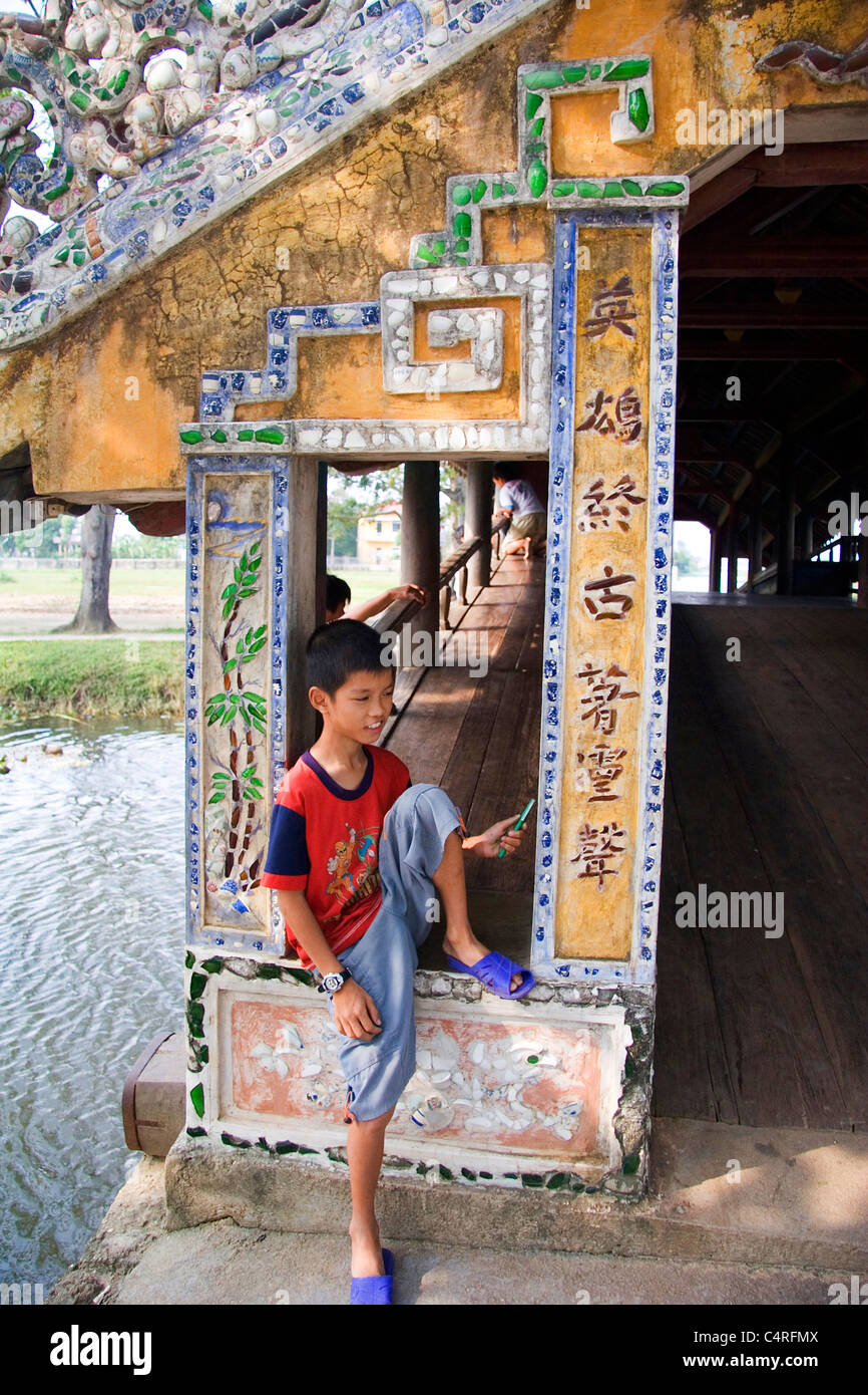 A local Vietnamese boy relaxing on the Thanh Toan Bridge, Hue, Vietnam Stock Photo