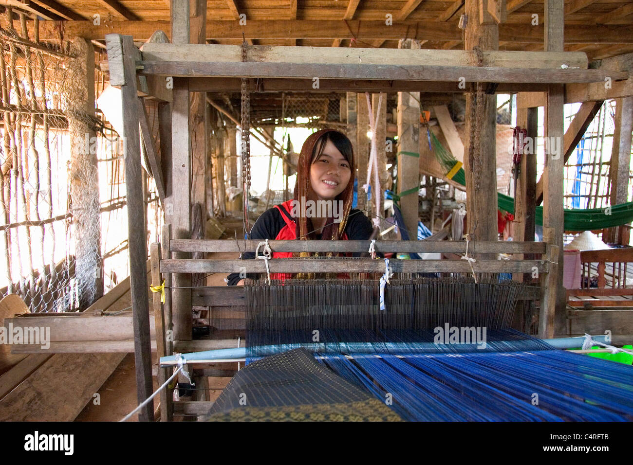 A young girl at work weaving on a loom, Cambodia Stock Photo