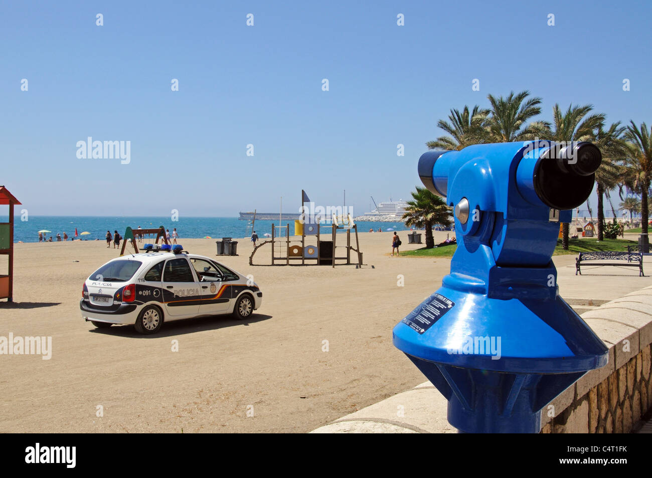 Telescope on the edge of Malagueta beach looking towards a police car, the port and Mediterranean sea, Malaga, Spain, Europe. Stock Photo