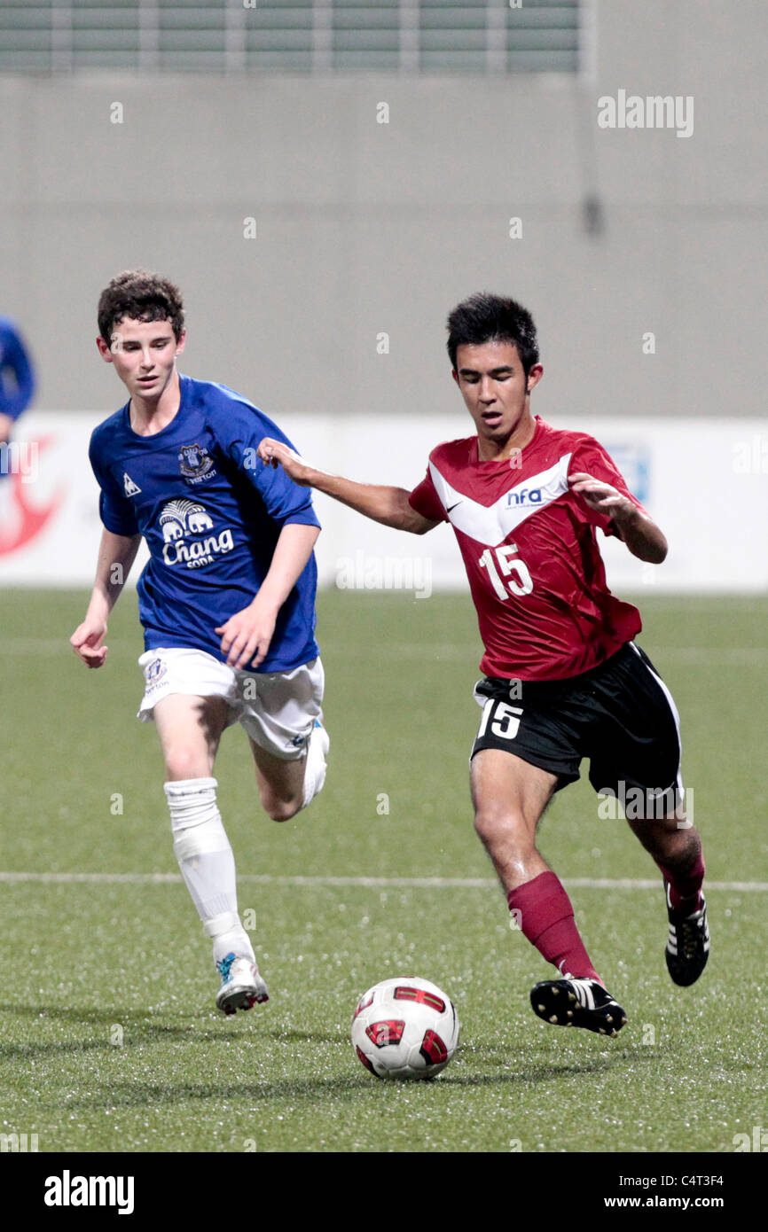 Bryan Neubronner of Singapore U16(red) gets past Charley Edge during the 23rd Canon Lion City Cup. Stock Photo