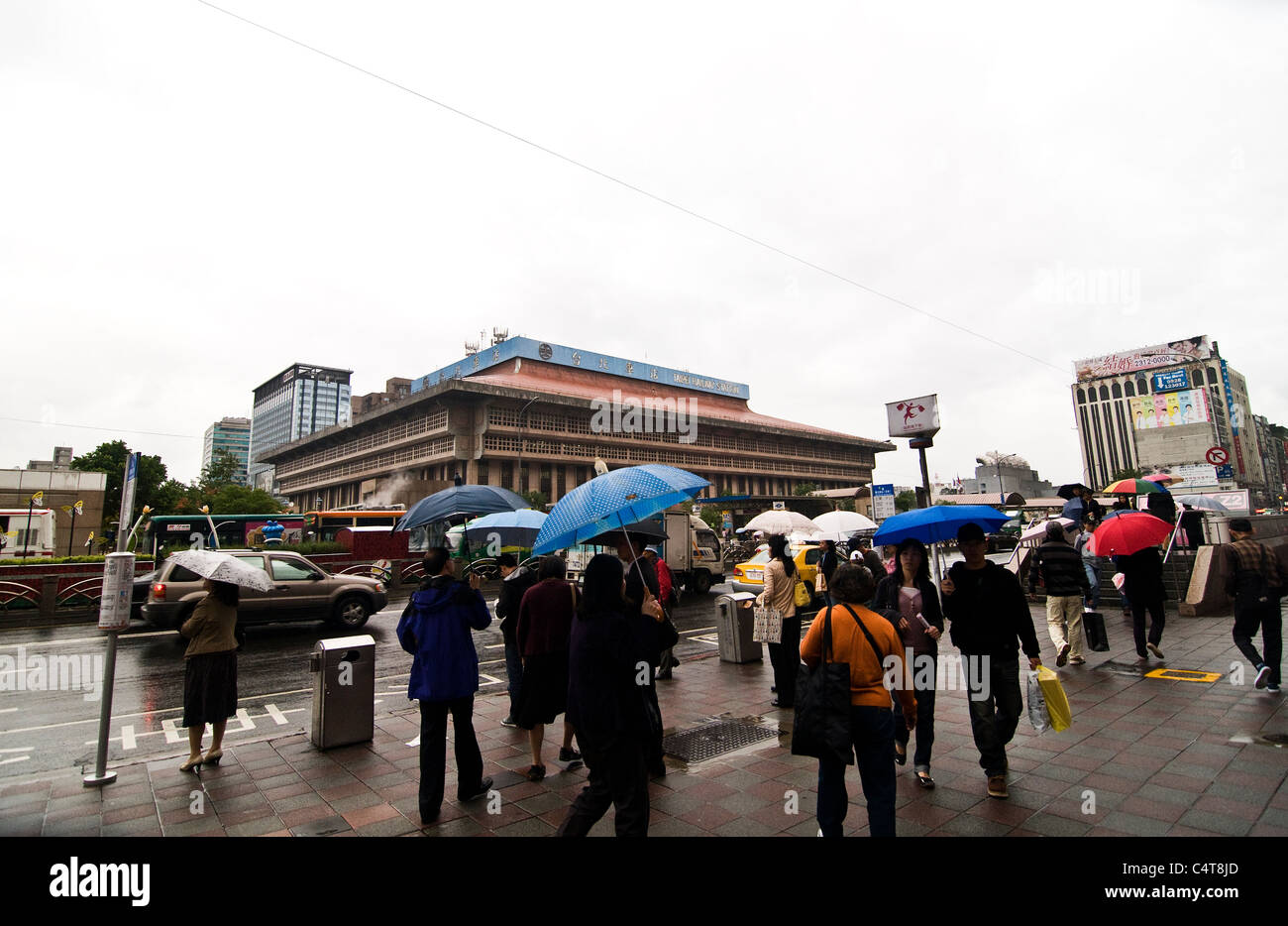 Pedestrians walking in front of Taipei's railway station on a rainy day. Stock Photo