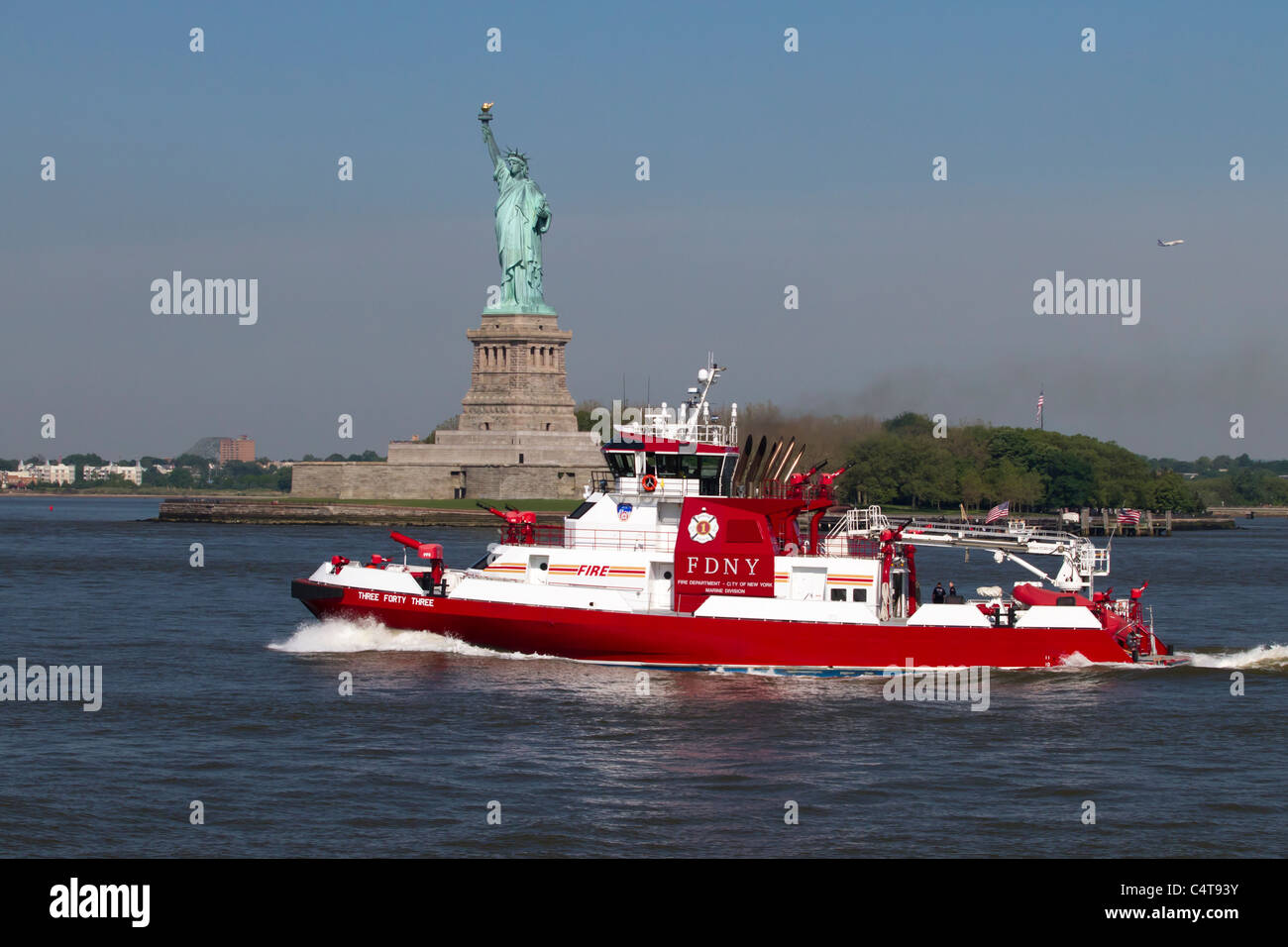 NYFD fire boat 343 named in remembrance of the number of firefighters who perished during 9/11 passing the Statue of Liberty Stock Photo