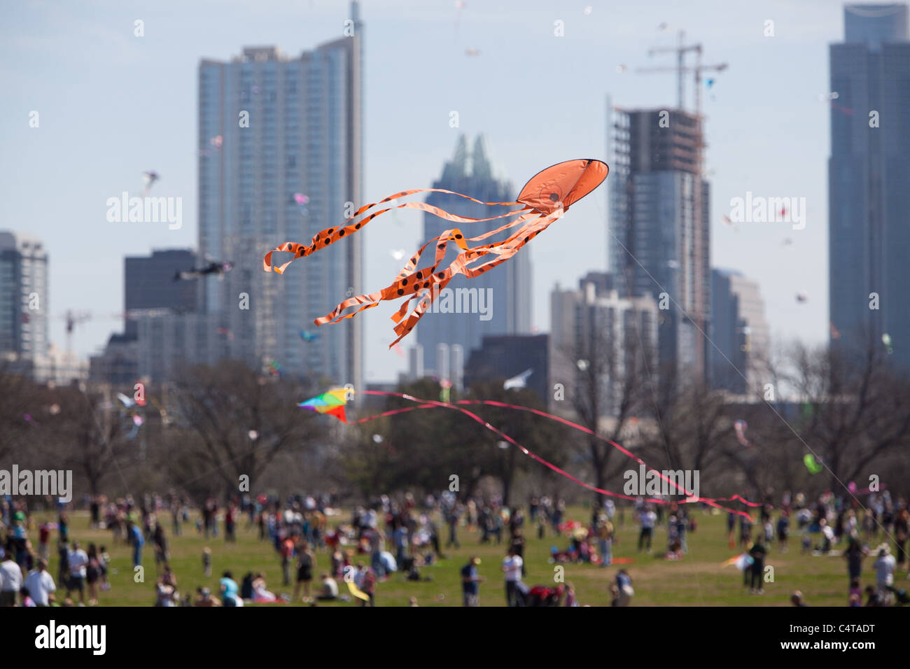 An orange octopus kite flys in front of the Austin skyline at the Austin Kite Festival in Zilker Park Stock Photo