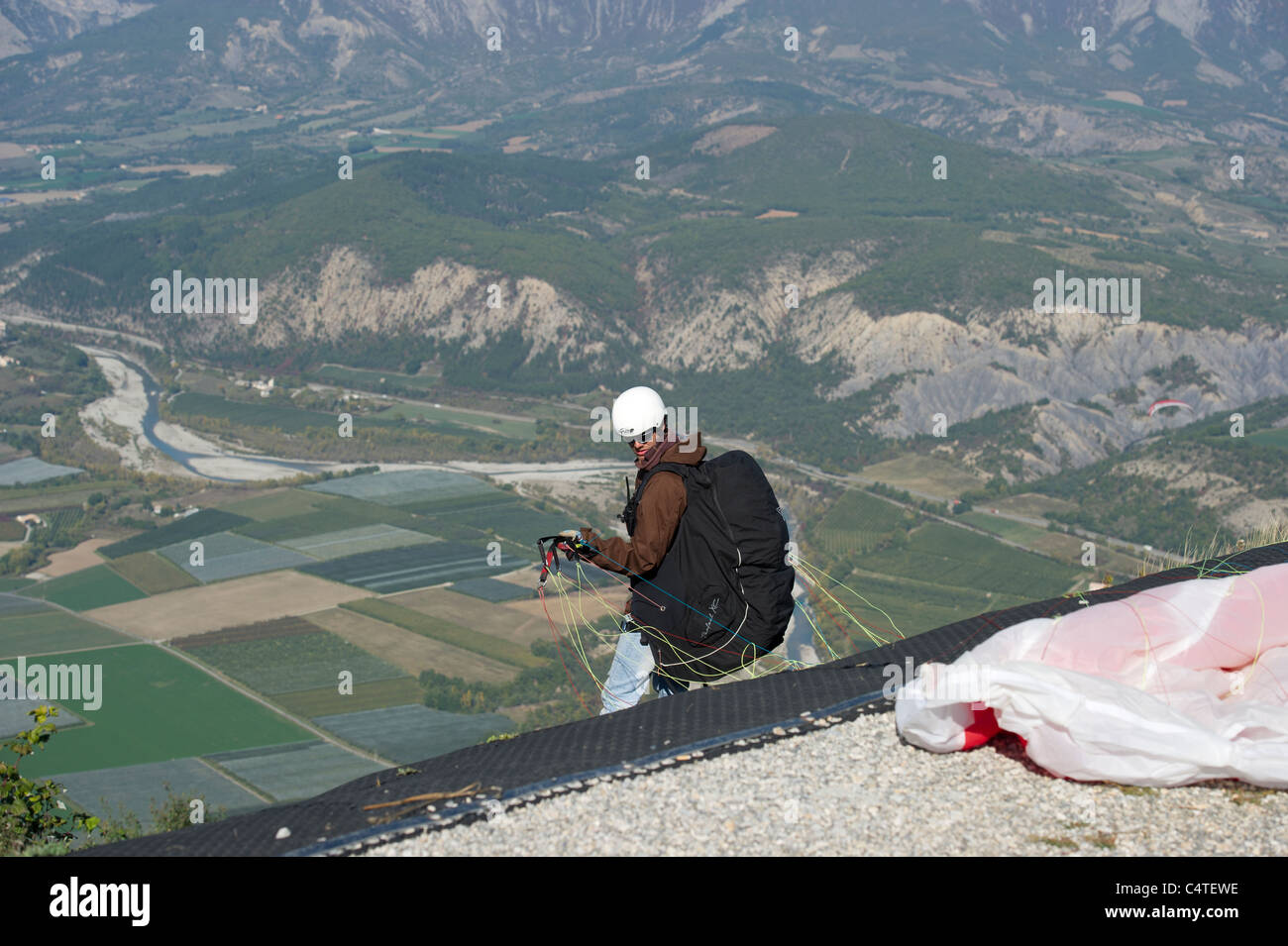 Male paraglider pilot makes final checks on his canopy and lines prior to launching from the summit of Le Chabre, Provence. Stock Photo