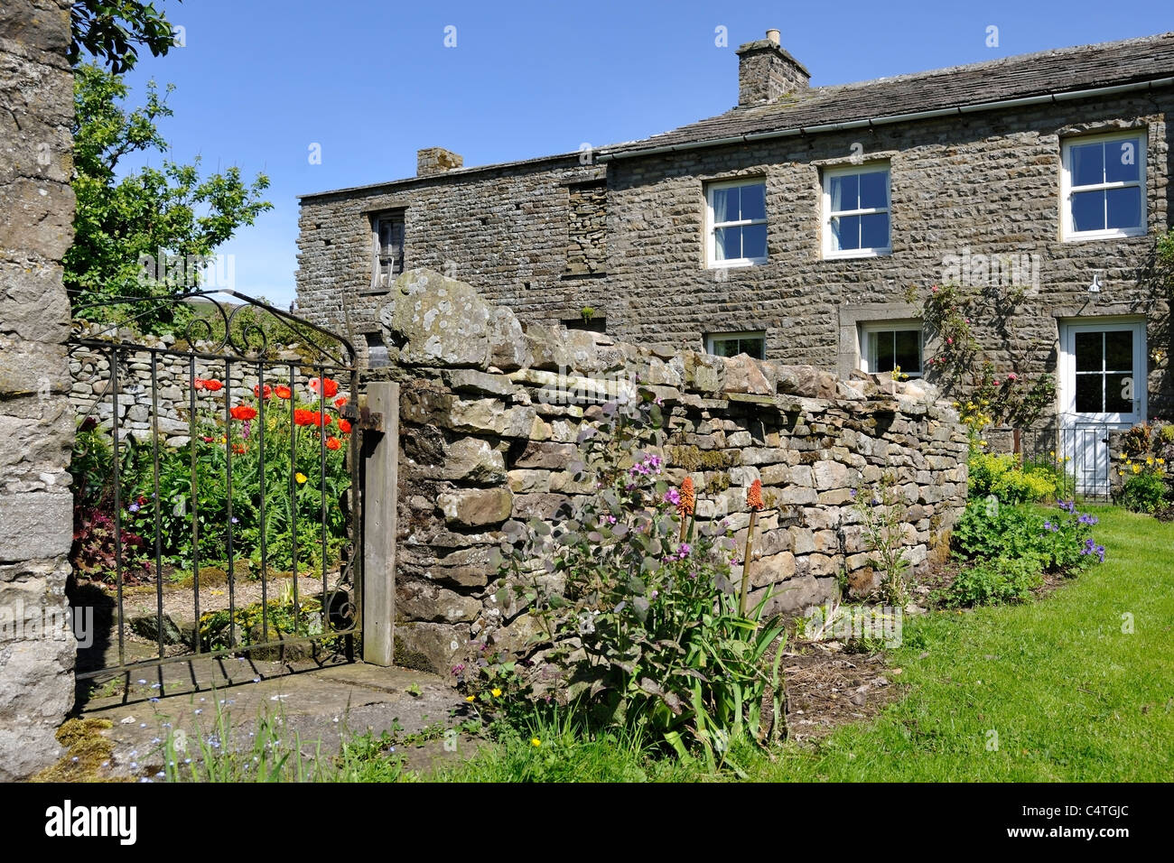 Drystone wall marking the boundary of a village garden in Thwaite, Swaledale, Yorkshire, England Stock Photo