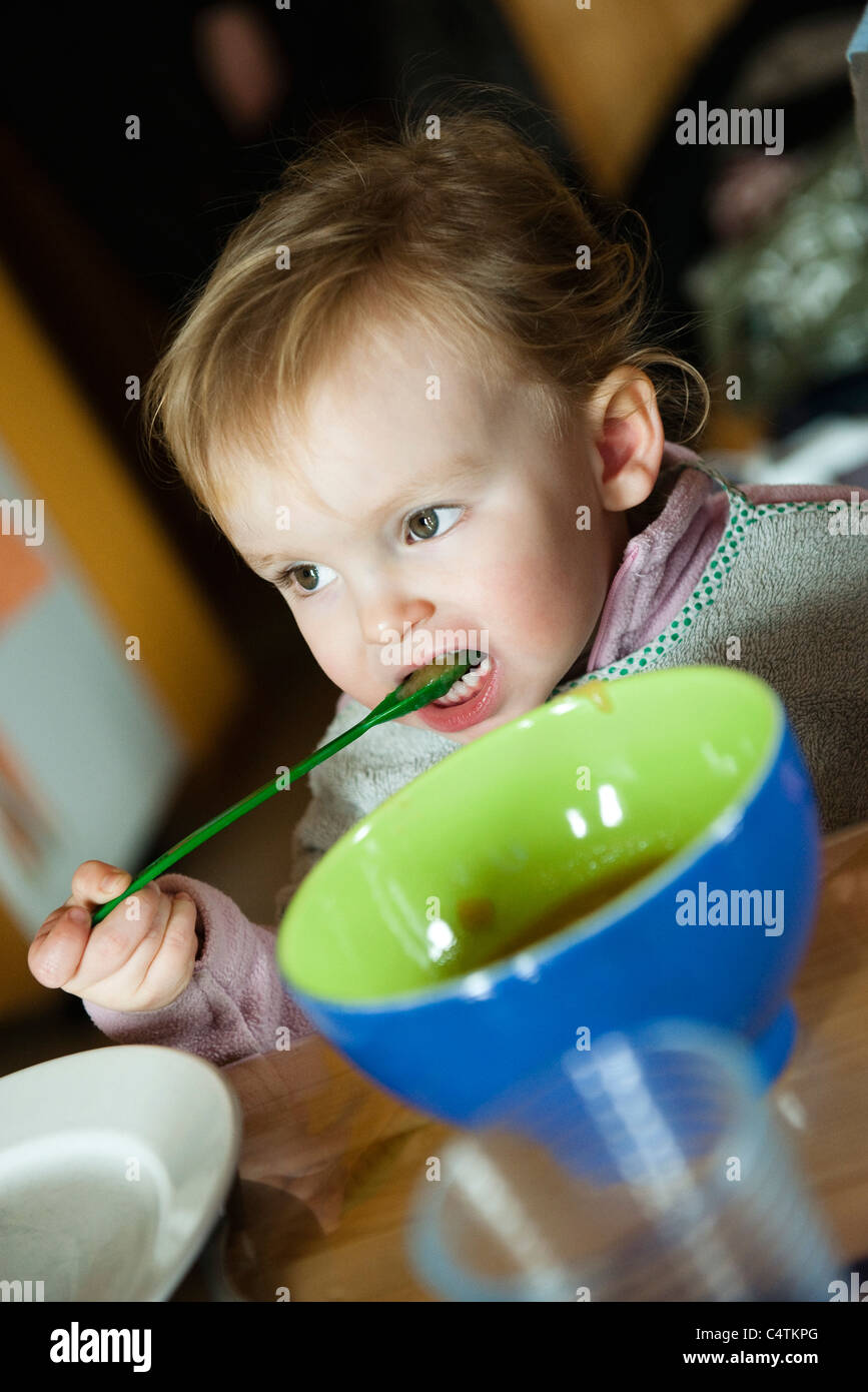 Toddler girl feeding herself with spoon Stock Photo