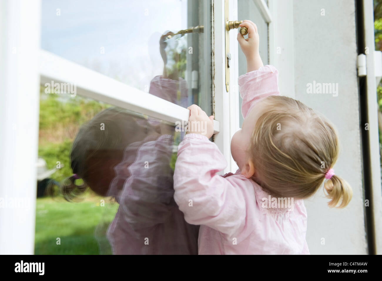 Toddler girl reaching to open door Stock Photo Alamy