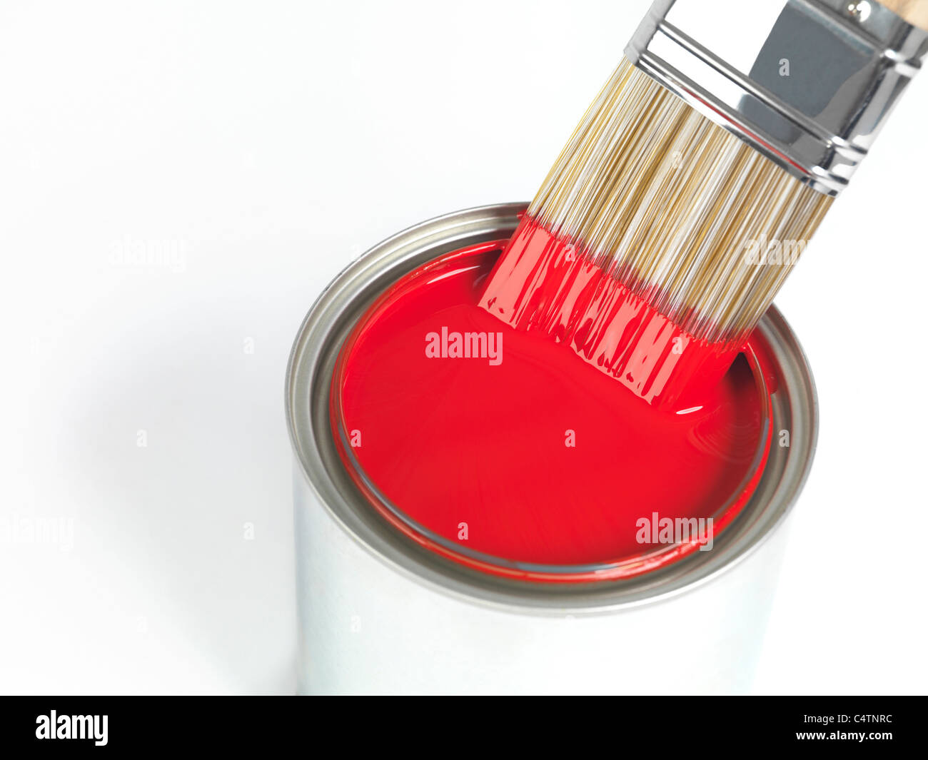 Painting brush dipped in can of red paint isolated on white background