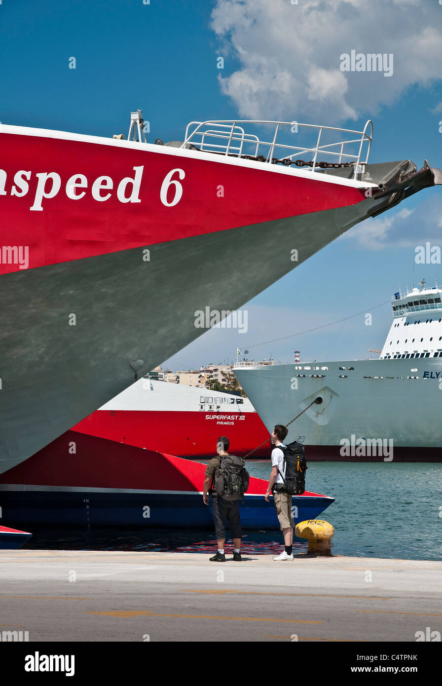 Back packers admiring a high speed ferry in the harbour at Pireaus, Athens, Greece. Stock Photo